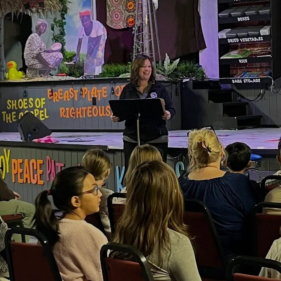 A teacher speaking to students from the platform during a chapel program