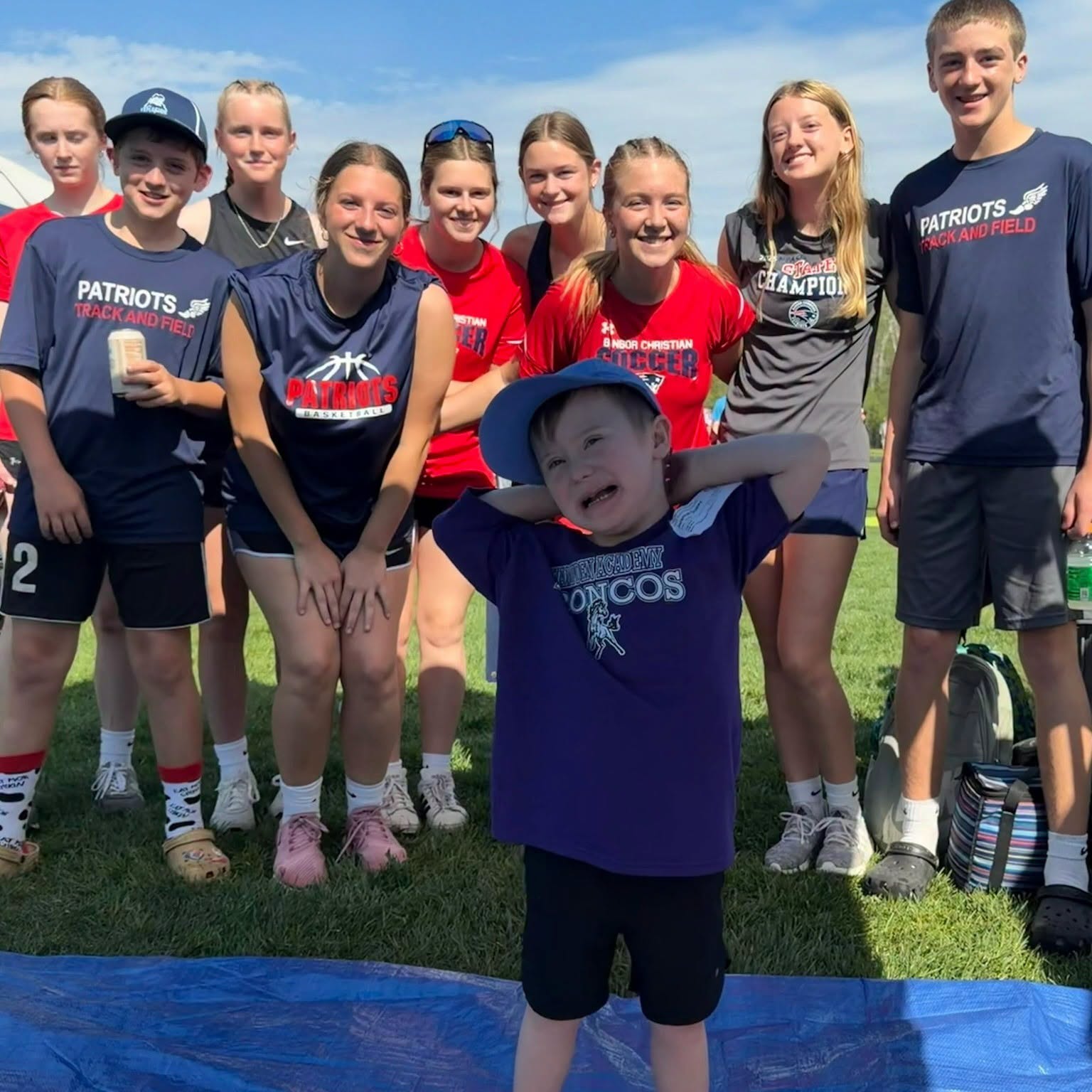 Patriots track and field athletes gathered with a younger sibling at a meet