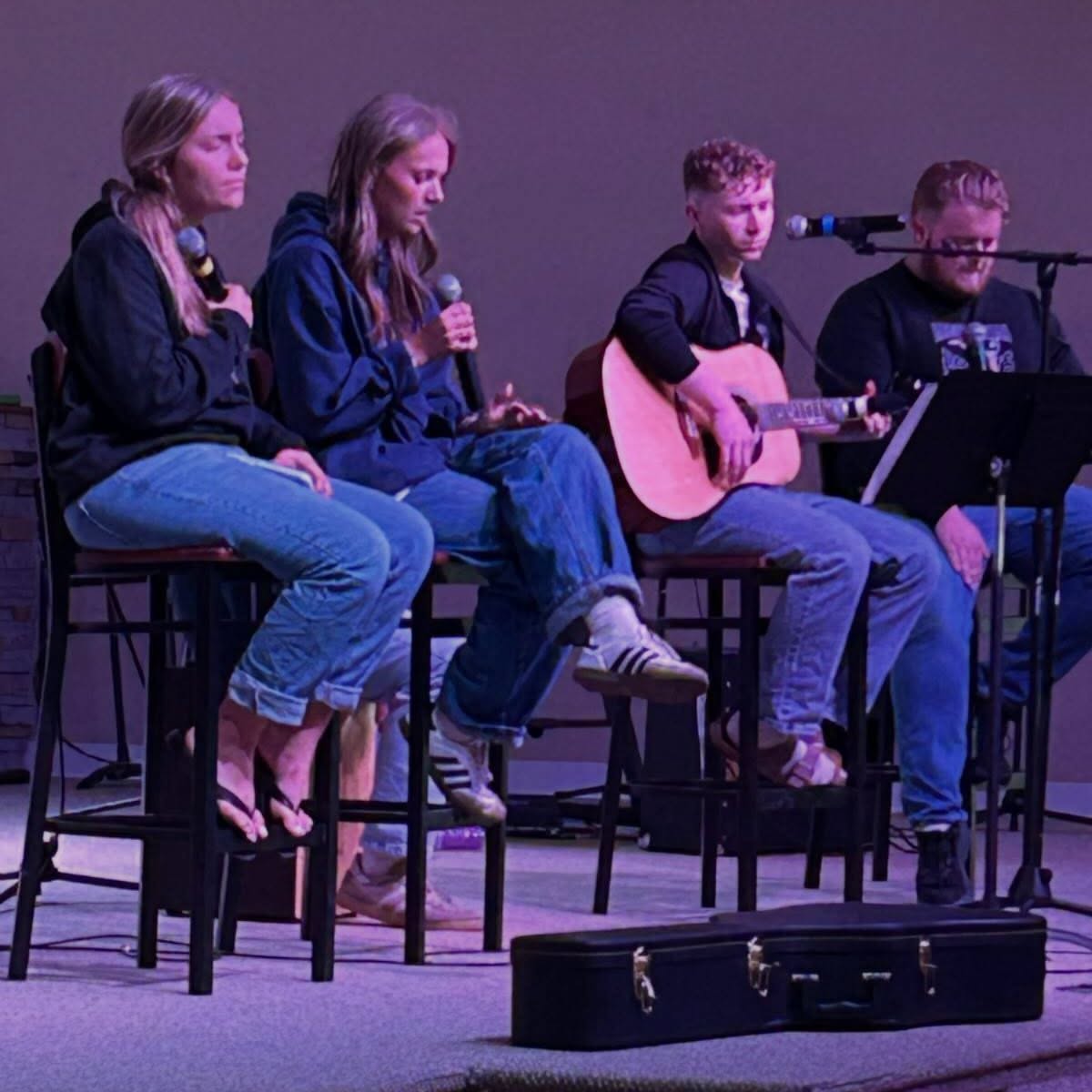 Students leading worship with guitar and microphones during a chapel service