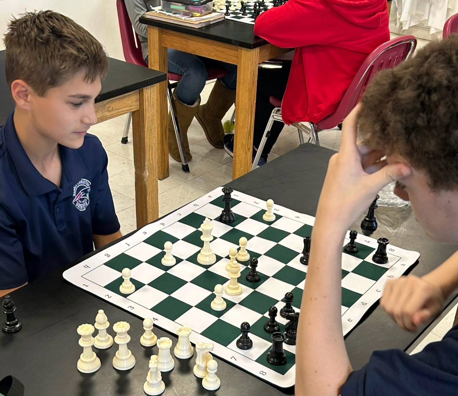 Two middle school students playing a game of chess in class